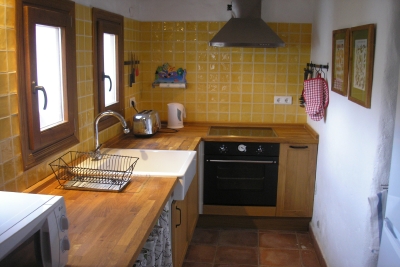 Bright rustic style kitchen with wooden countertop and cupboard curtains.