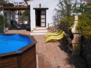 Utsikt över pool och terrass med huset och den omgivande landsbygden i bakgrunden.