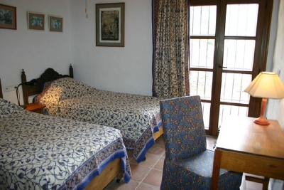 Andra sovrum med två enkelsängar, skrivbord och dörrar som leder ut på baksidan terrass.